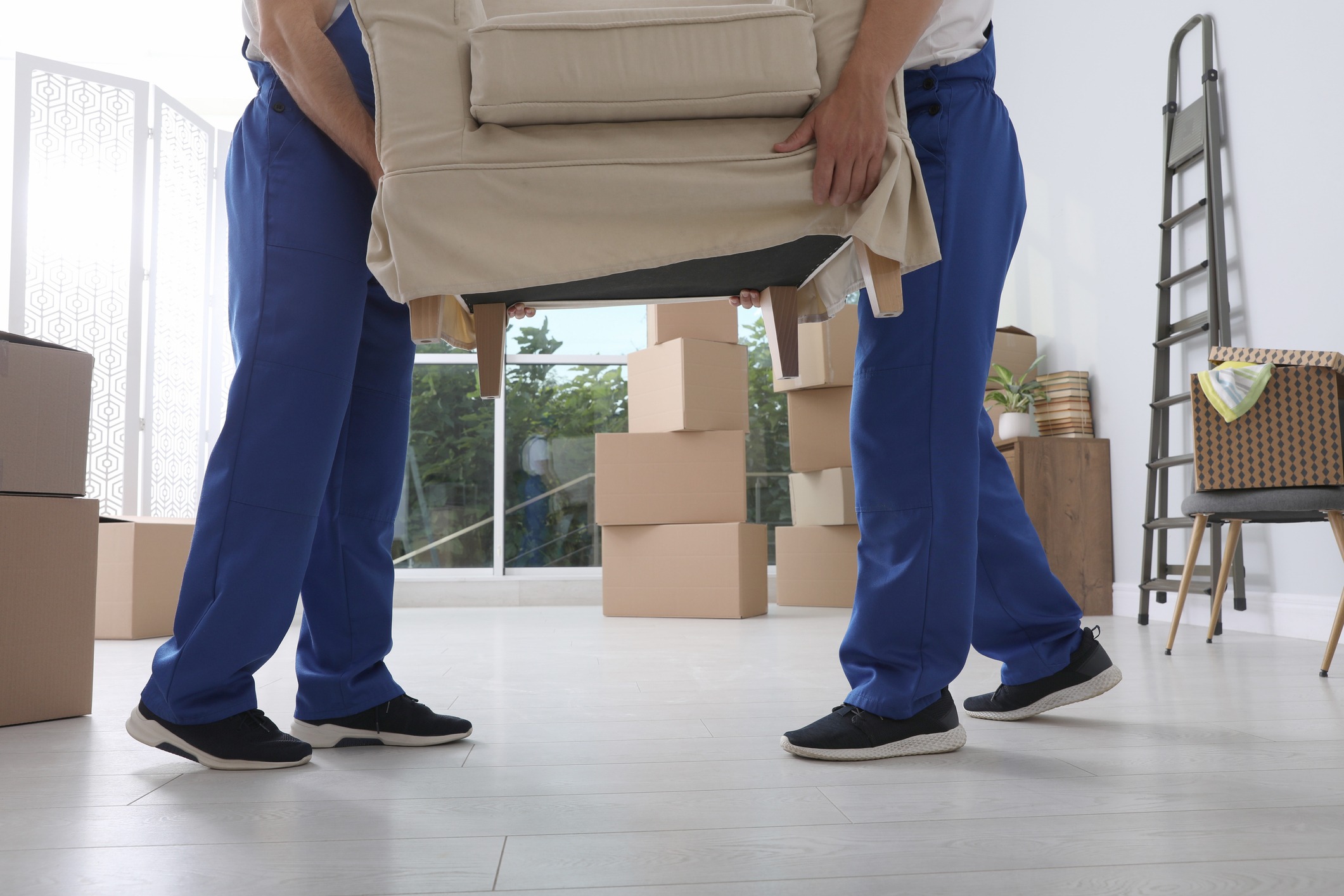 Two moving technicians work together to place a couch in a client's new home.